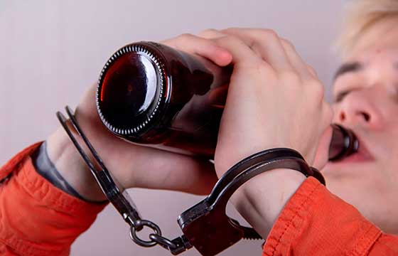 подросток в наручниках пьет пиво из бутылки